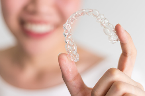 A woman holding her Invisalign clear aligner