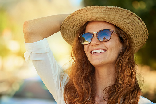 Woman wearing sun glasses and sun hat outside on a sunny day